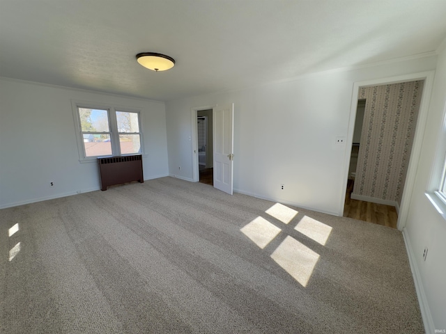 spare room with radiator, baseboards, and carpet