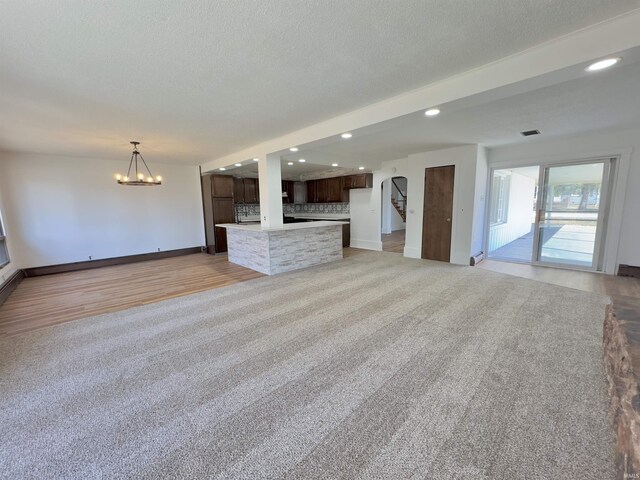 unfurnished living room with visible vents, recessed lighting, light wood-style flooring, an inviting chandelier, and a textured ceiling