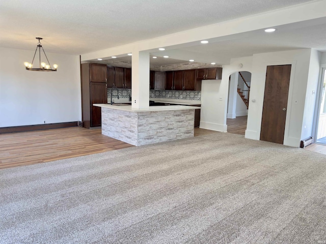 kitchen featuring tasteful backsplash, dark brown cabinetry, light colored carpet, light countertops, and recessed lighting