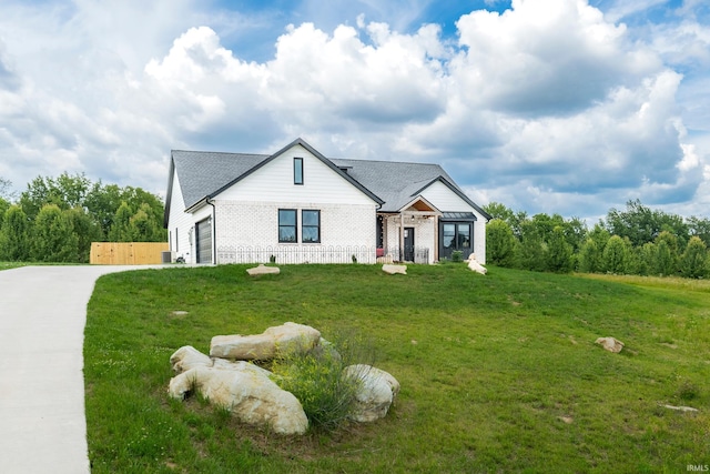 modern farmhouse style home featuring brick siding, driveway, a front lawn, and roof with shingles