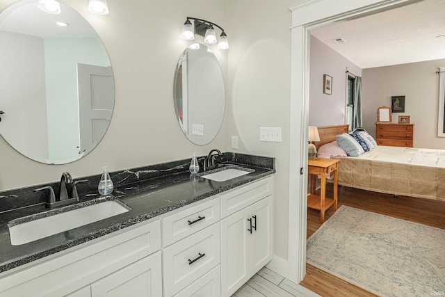 ensuite bathroom with double vanity, wood finished floors, ensuite bathroom, and a sink