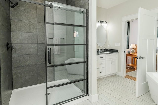 bathroom featuring a soaking tub, vanity, wood finished floors, and a shower stall