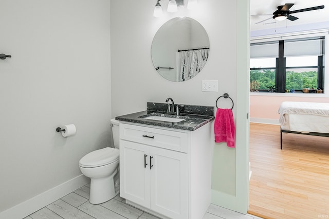 full bath featuring vanity, wood finished floors, baseboards, ceiling fan, and toilet