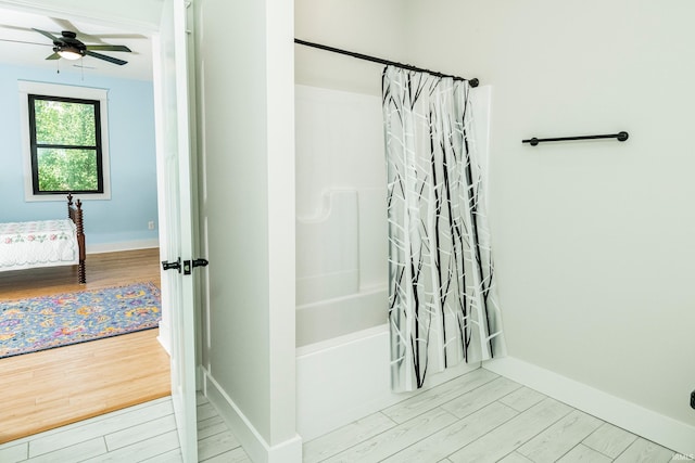 bathroom featuring wood finished floors, baseboards, shower / tub combo with curtain, and ceiling fan