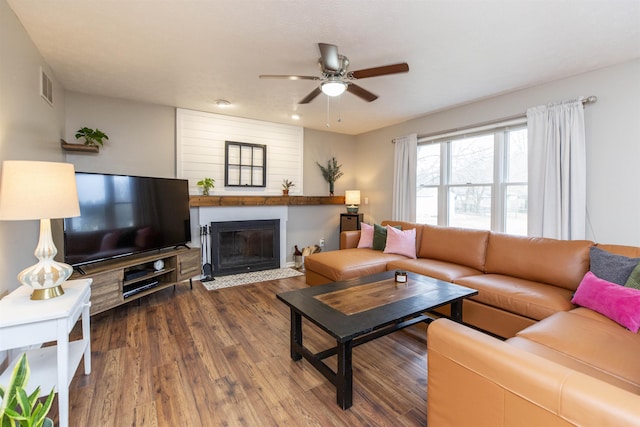 living room featuring visible vents, a fireplace with flush hearth, dark wood-type flooring, and ceiling fan