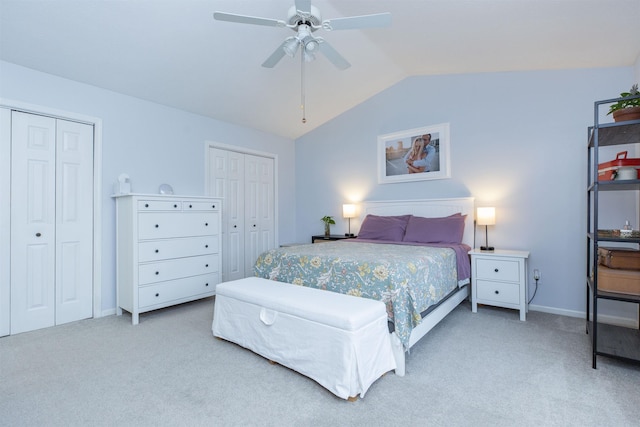 bedroom featuring carpet, lofted ceiling, multiple closets, and a ceiling fan