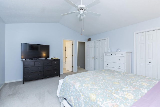 bedroom featuring a ceiling fan, baseboards, vaulted ceiling, light colored carpet, and two closets