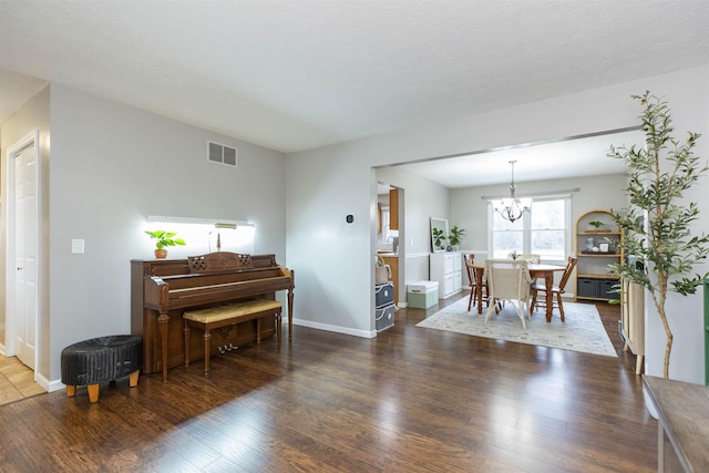 interior space with visible vents, baseboards, an inviting chandelier, and wood finished floors