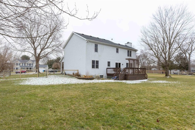 rear view of house featuring a deck, a chimney, and a yard