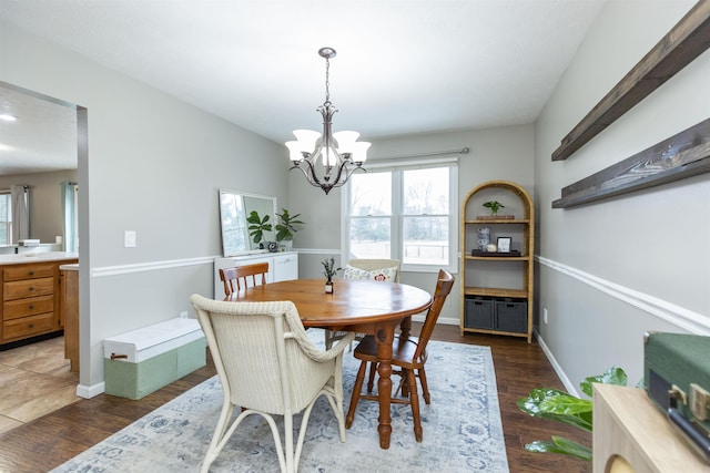 dining space featuring light wood-type flooring, baseboards, and an inviting chandelier