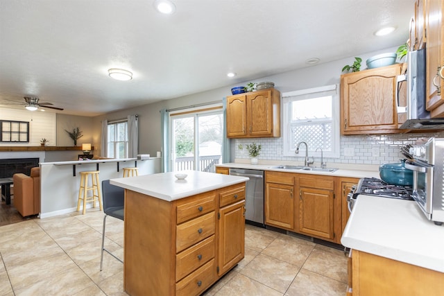 kitchen featuring a sink, tasteful backsplash, stainless steel appliances, a breakfast bar area, and light countertops