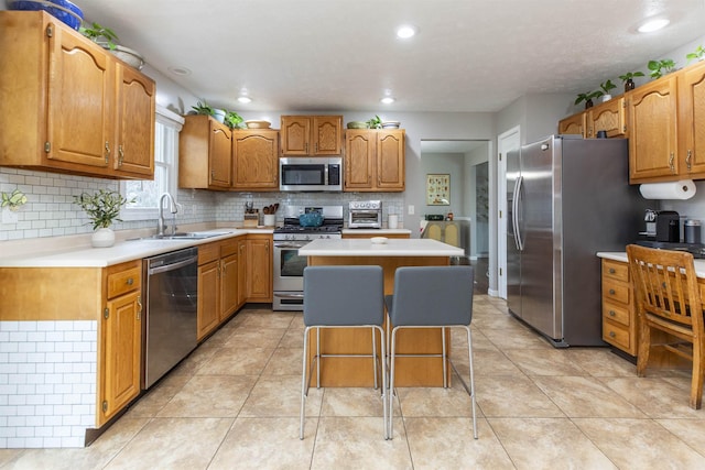 kitchen with a kitchen island, backsplash, stainless steel appliances, and a sink