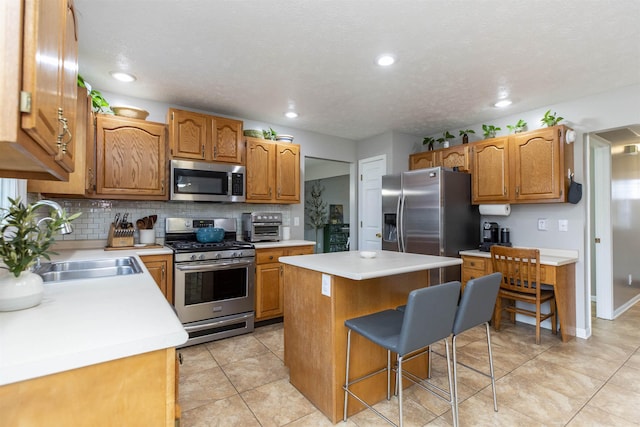 kitchen with a breakfast bar area, a kitchen island, a sink, stainless steel appliances, and tasteful backsplash