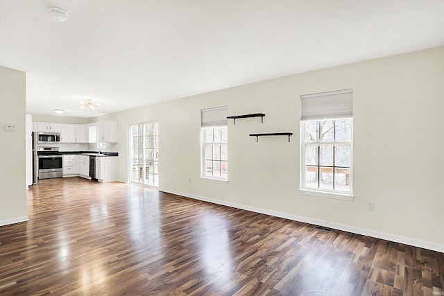 904 S Deer Run, Ellettsville, IN 47429 - unfurnished living room with plenty of natural light, dark wood-type flooring, and baseboards