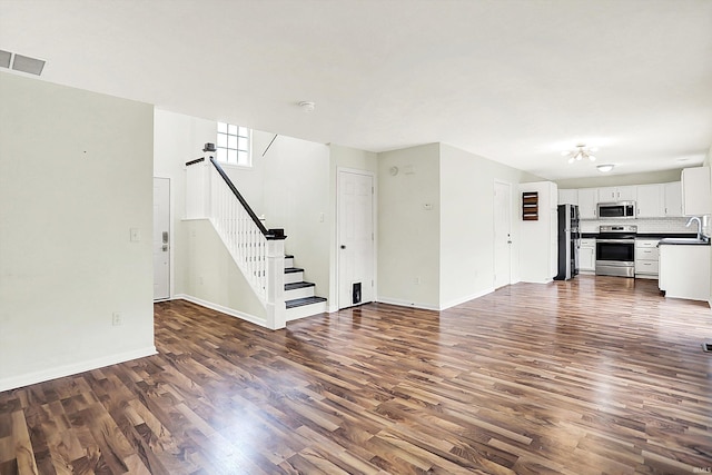 904 S Deer Run, Ellettsville, IN 47429 - unfurnished living room with visible vents, a sink, dark wood-style floors, baseboards, and stairs