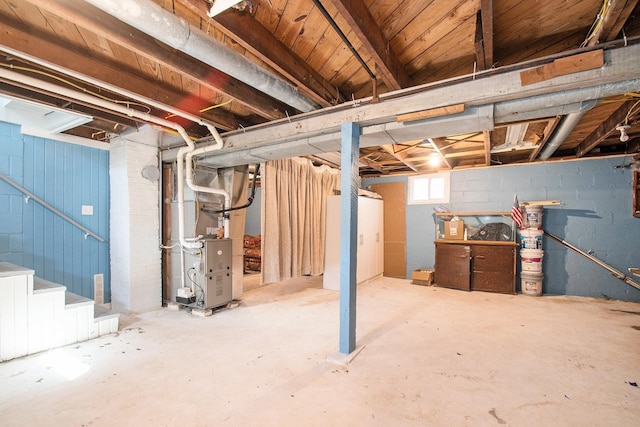 basement featuring heating unit, concrete block wall, and stairs