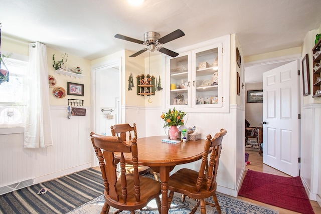 dining room featuring a ceiling fan and wainscoting