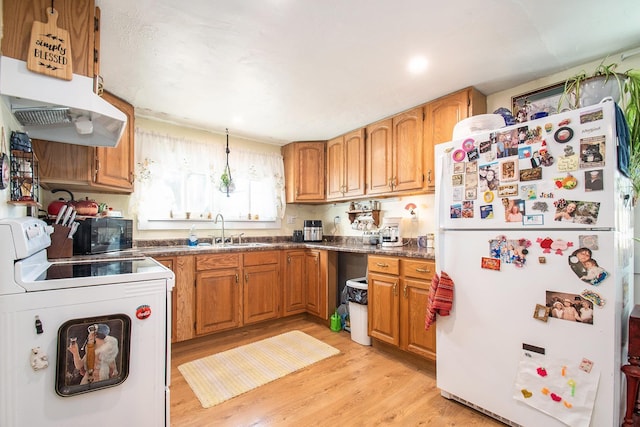 kitchen featuring brown cabinetry, light wood finished floors, white appliances, and a sink