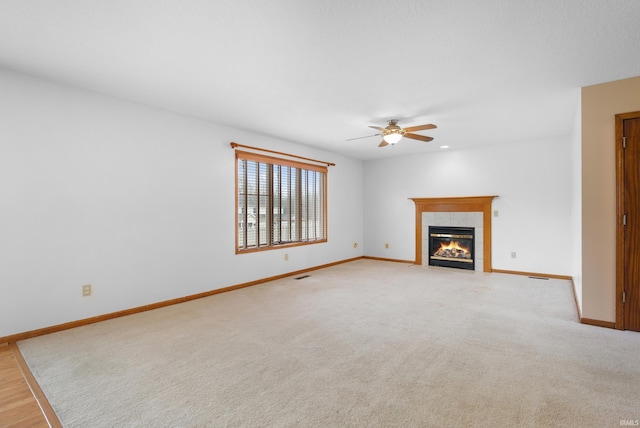 unfurnished living room featuring light colored carpet, a fireplace, baseboards, and ceiling fan