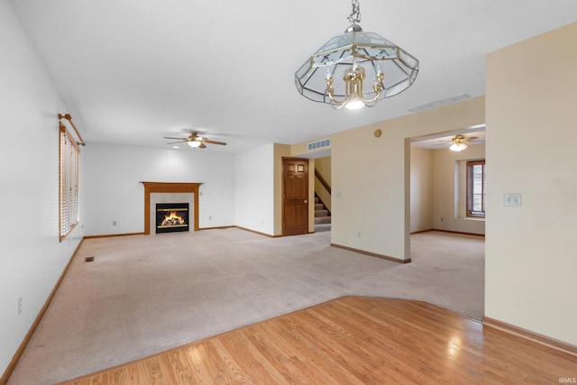 unfurnished living room with visible vents, baseboards, stairway, carpet floors, and a fireplace