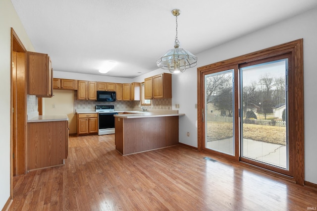 kitchen featuring light wood-style floors, a peninsula, black microwave, and electric stove