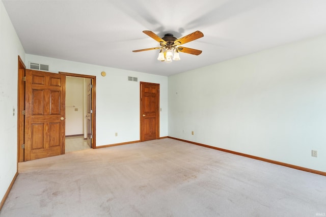 unfurnished bedroom featuring visible vents, light colored carpet, a ceiling fan, and baseboards