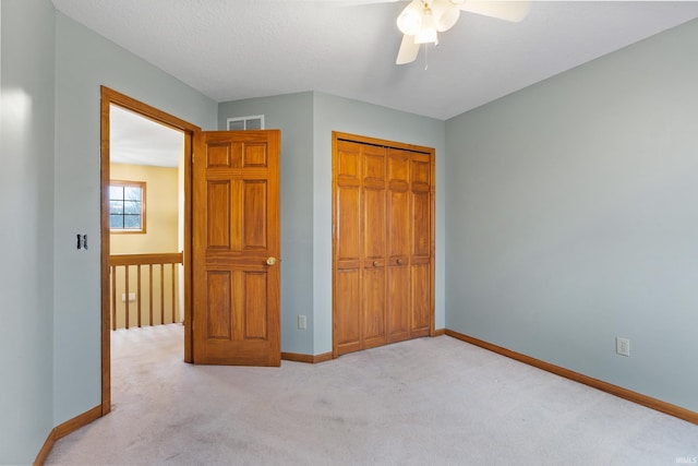 unfurnished bedroom featuring a textured ceiling, light colored carpet, a closet, and baseboards