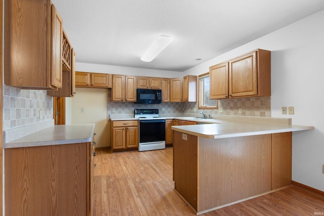 kitchen with a peninsula, electric range, light wood finished floors, and black microwave