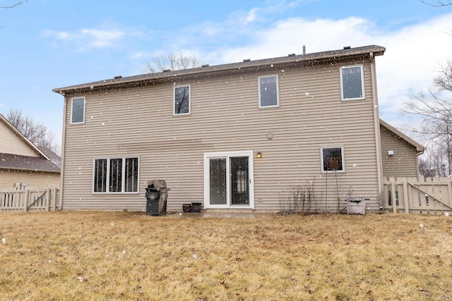 back of property with a lawn and fence