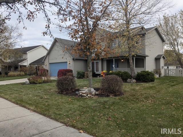 view of front of home with a front yard, an attached garage, fence, and a porch