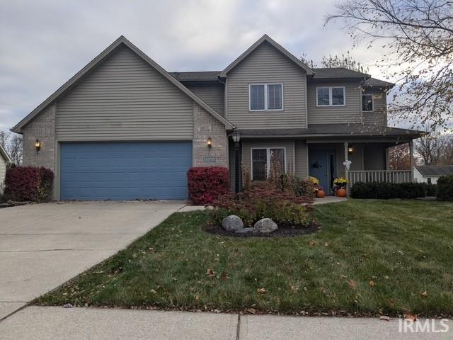 view of front of property with covered porch, concrete driveway, a front yard, a garage, and brick siding