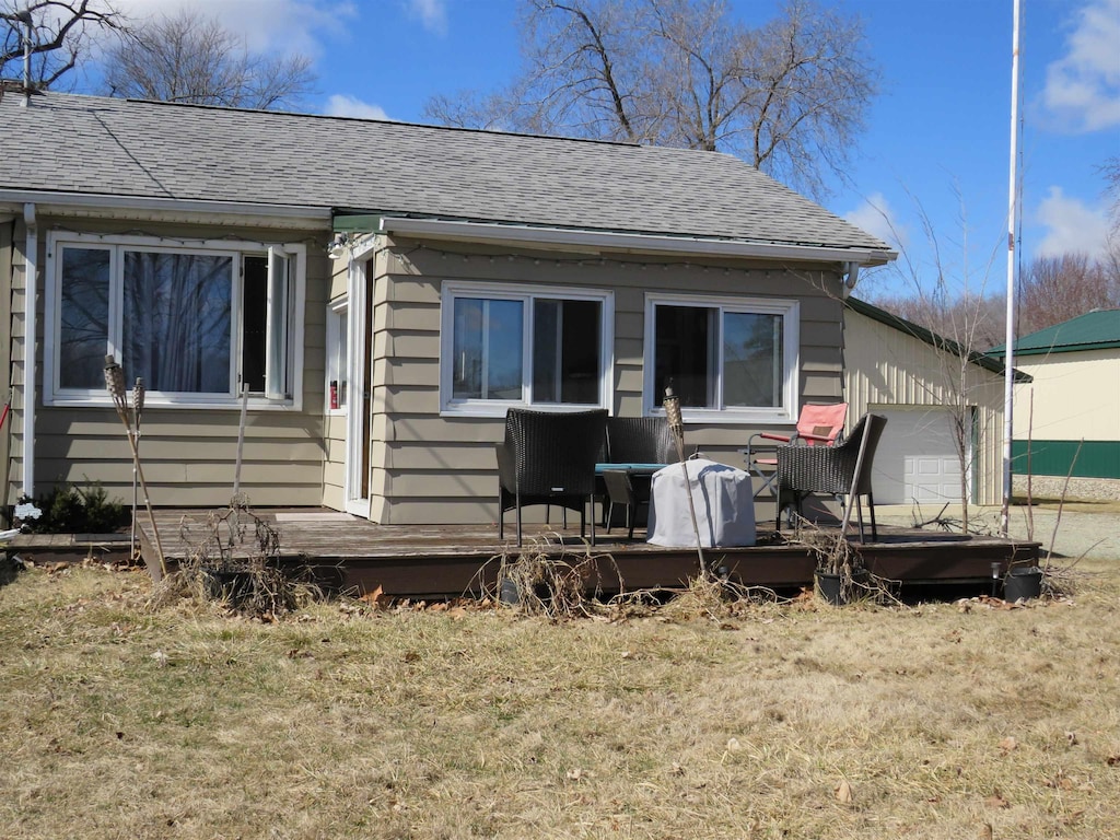 back of property featuring a lawn and a shingled roof