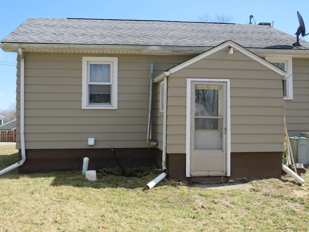 back of property with a yard, roof with shingles, and cooling unit