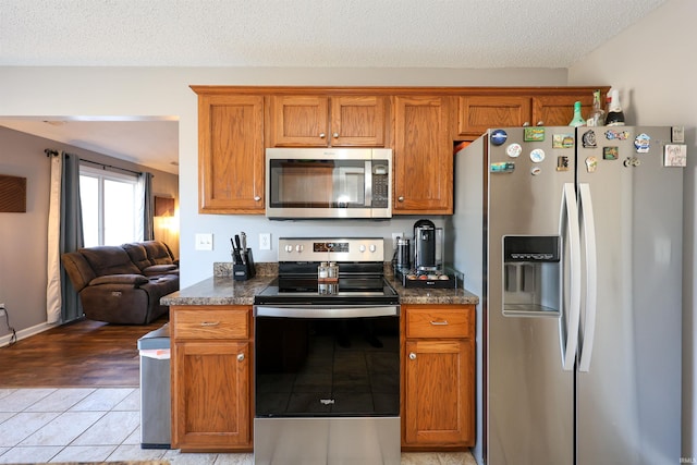 kitchen with dark countertops, appliances with stainless steel finishes, and brown cabinetry