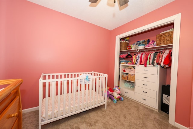 bedroom with carpet, baseboards, ceiling fan, a nursery area, and a closet