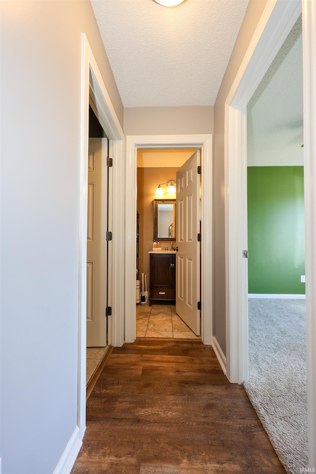 hall with wood finished floors, baseboards, carpet floors, and a textured ceiling