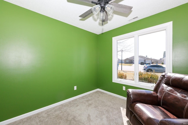 living area featuring visible vents, carpet floors, baseboards, and a ceiling fan