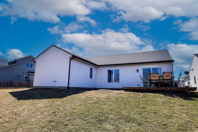 rear view of house featuring a lawn, a deck, and fence