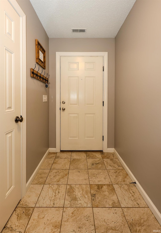 entryway featuring baseboards, visible vents, and a textured ceiling