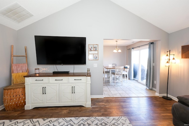 living area featuring vaulted ceiling, wood finished floors, visible vents, and a chandelier