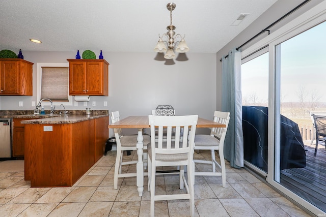 kitchen featuring an inviting chandelier, a sink, stainless steel dishwasher, dark countertops, and brown cabinets