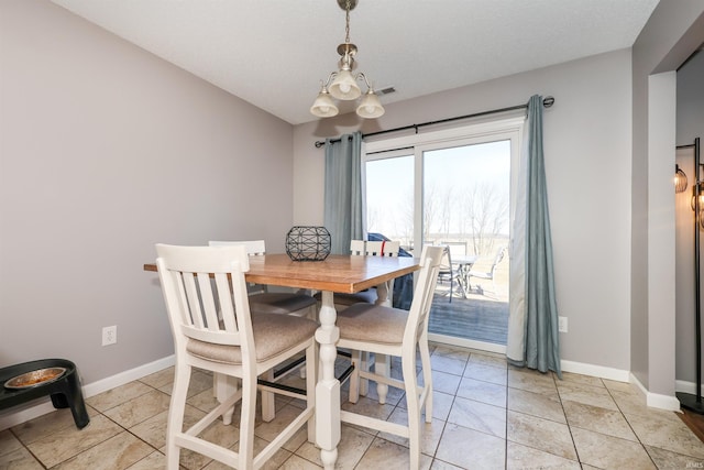 dining area with light tile patterned floors, baseboards, and a notable chandelier