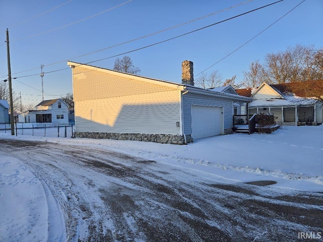 snow covered property featuring a detached garage