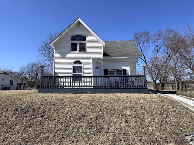 view of front of home with a wooden deck and roof with shingles