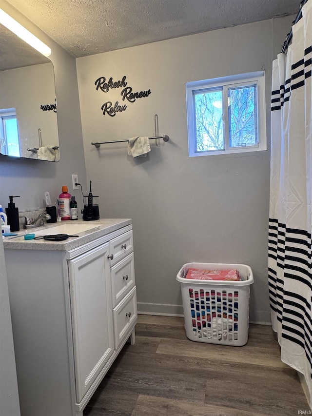 bathroom with baseboards, a textured ceiling, wood finished floors, and vanity