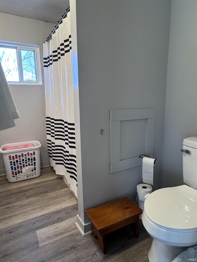 bathroom with toilet, a shower with shower curtain, and wood finished floors