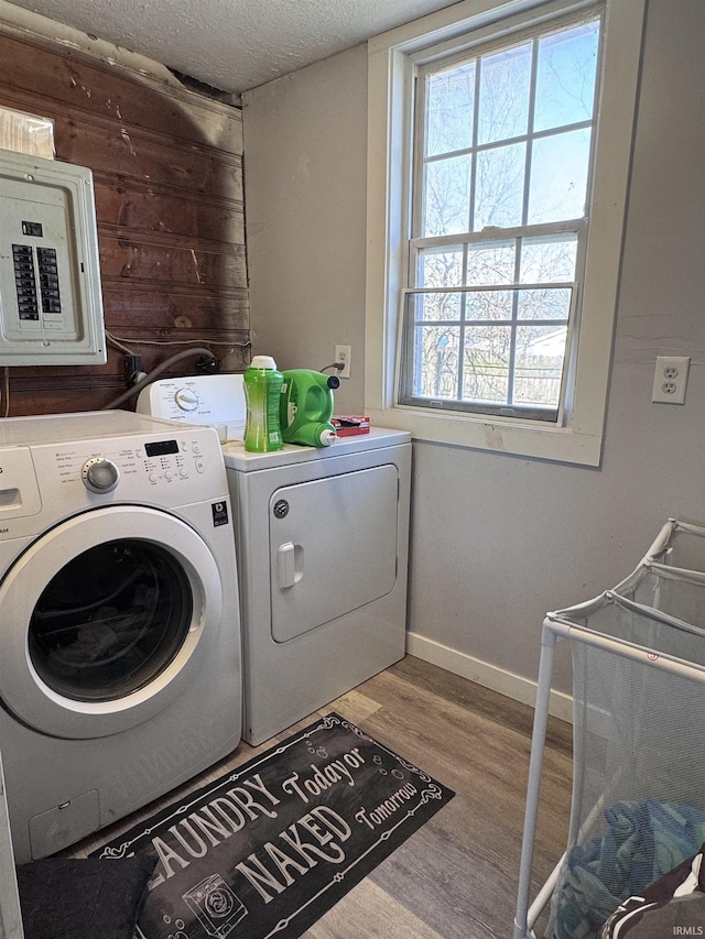 washroom with wood finished floors, laundry area, electric panel, separate washer and dryer, and a textured ceiling