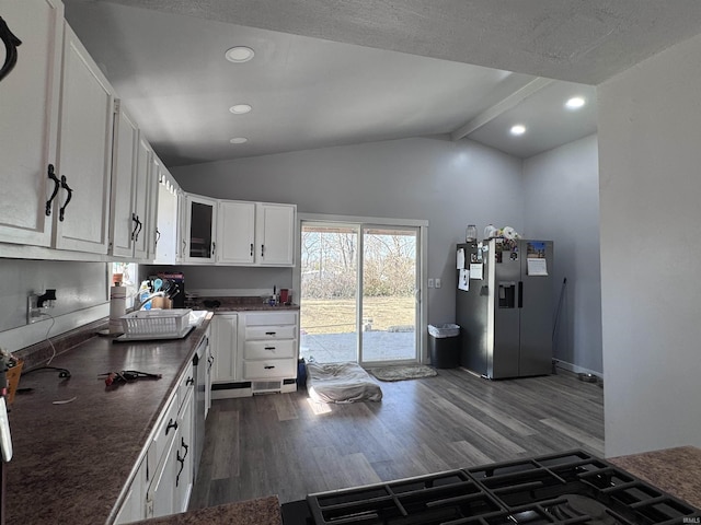 kitchen with stainless steel refrigerator with ice dispenser, lofted ceiling with beams, dark countertops, white cabinetry, and dark wood-style flooring