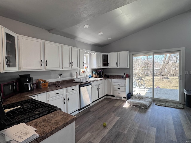 kitchen with stainless steel dishwasher, dark countertops, glass insert cabinets, lofted ceiling, and dark wood-style flooring