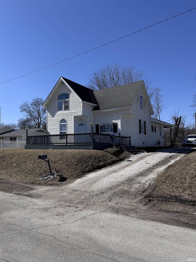 view of front of property featuring a shingled roof, driveway, and fence